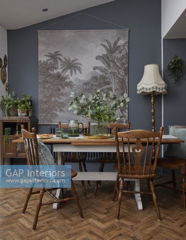 Dining area with vintage wooden furniture, dark grey walls and botanical artwork.