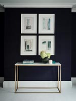 Metal table and display of artwork on black painted wall 