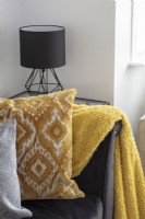 Detail of yellow blankey and gold cushion on black sofa
