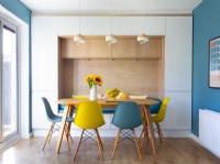 Blue and yellow chairs around wooden dining table with alcove seat