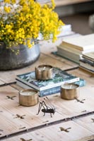 Metal bug and tealights on wooden coffee table 