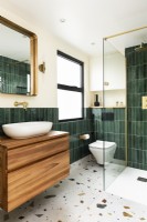 Contemporary modern bathroom with green vertical tiles, terrazzo floor tiles and brass fittings, taps