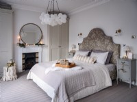 Neutral bedroom with decorative headboard and feature light